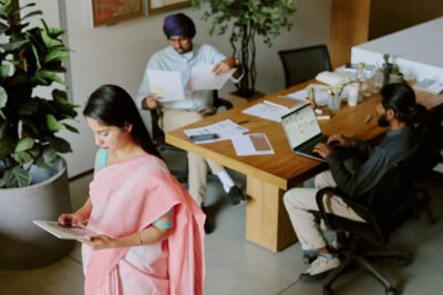 High angle shot of small group of IT specialist working with diagrams and database using different digital devices and sources of information